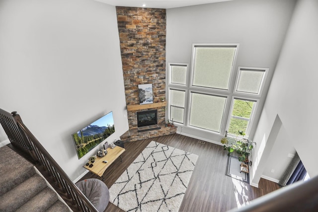 living room with a fireplace, dark wood-type flooring, and a high ceiling