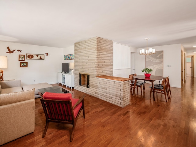 living room with a stone fireplace, hardwood / wood-style floors, and a chandelier