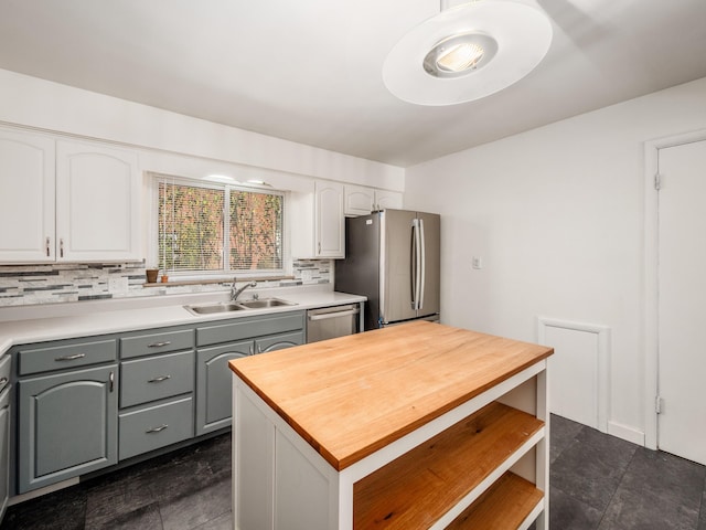 kitchen with backsplash, gray cabinets, sink, and appliances with stainless steel finishes