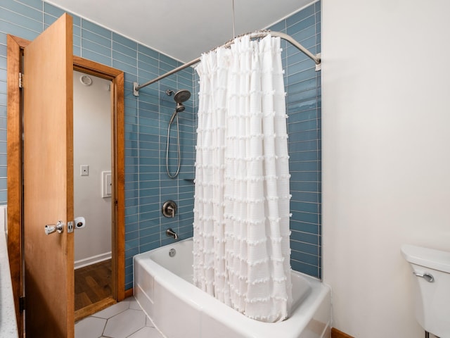 bathroom featuring tile patterned floors, toilet, shower / bathtub combination with curtain, and tile walls