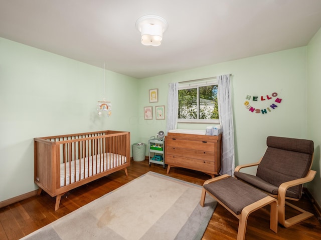 bedroom with dark hardwood / wood-style flooring and a nursery area