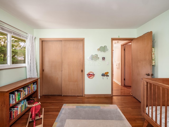 bedroom with a nursery area, hardwood / wood-style flooring, and a closet