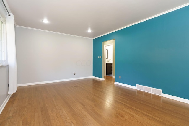 empty room featuring wood-type flooring and ornamental molding