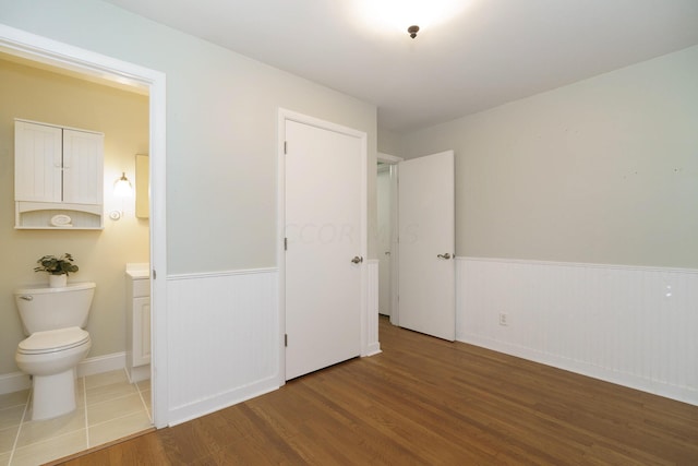 unfurnished bedroom featuring hardwood / wood-style floors and ensuite bath