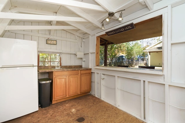 kitchen featuring vaulted ceiling with beams, white fridge, and sink