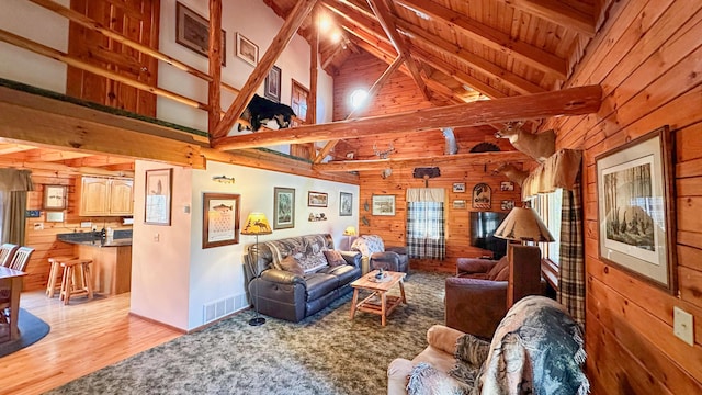 living room with light wood-type flooring, high vaulted ceiling, wooden ceiling, beamed ceiling, and wood walls