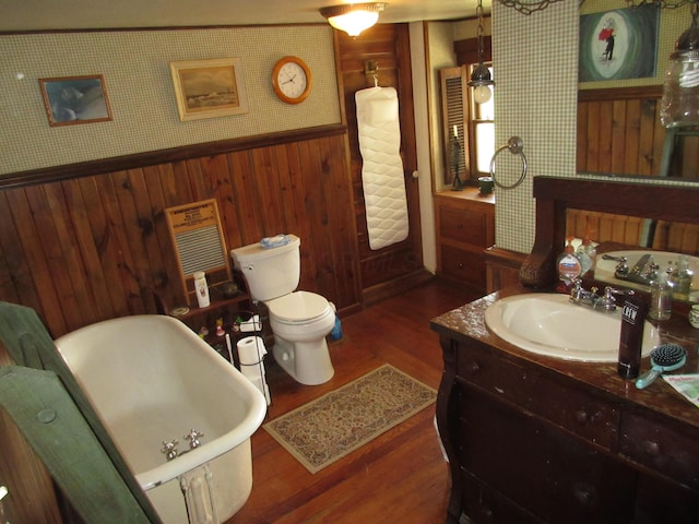 bathroom featuring vanity, hardwood / wood-style flooring, a bathing tub, and wood walls