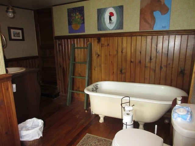 bathroom with a bath, hardwood / wood-style floors, toilet, and wood walls