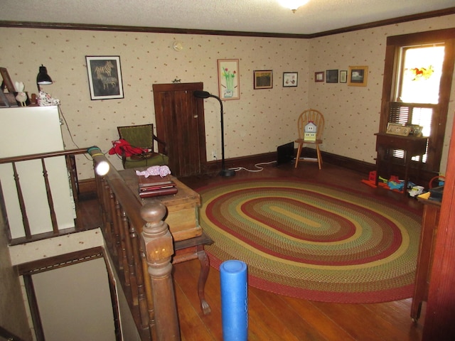 living room featuring a textured ceiling, wood-type flooring, and crown molding