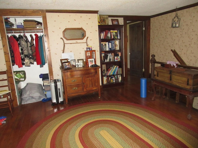 sitting room featuring dark hardwood / wood-style floors, ornamental molding, and a textured ceiling