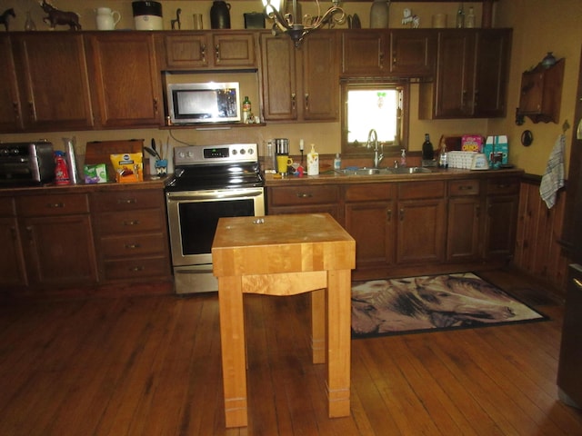 kitchen with a notable chandelier, sink, stainless steel appliances, and dark wood-type flooring