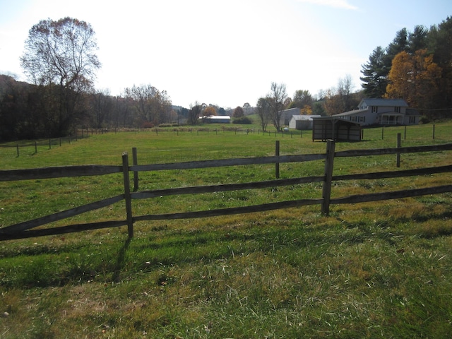 view of gate with a lawn and a rural view