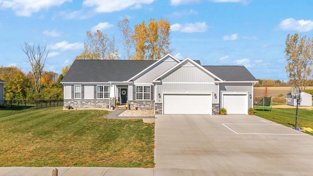 craftsman inspired home featuring a garage, a trampoline, and a front lawn