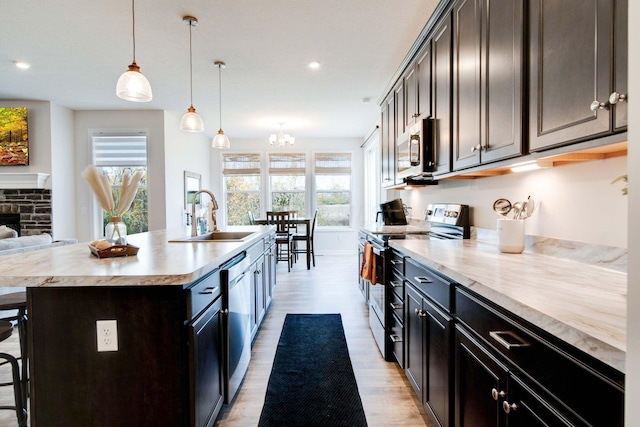 kitchen featuring sink, a fireplace, a breakfast bar, a center island with sink, and appliances with stainless steel finishes