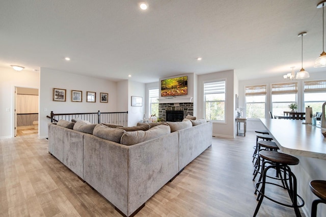 living room featuring a fireplace, a chandelier, and light wood-type flooring