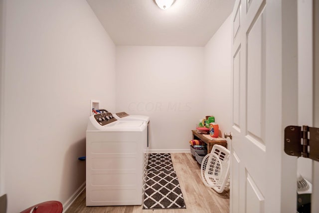 clothes washing area featuring light hardwood / wood-style flooring and washer and dryer