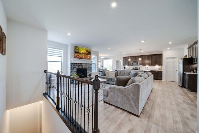 living room featuring a stone fireplace and light wood-type flooring