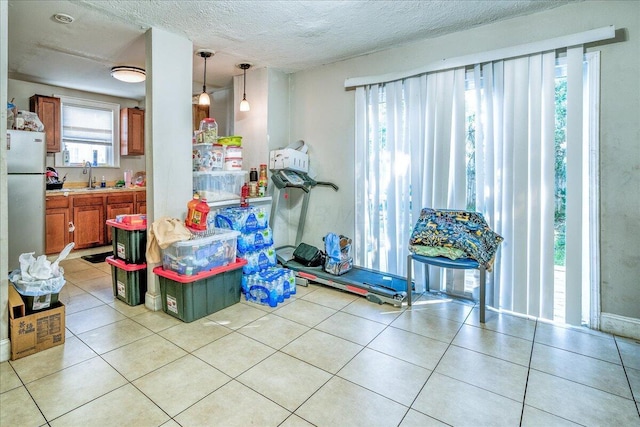 kitchen featuring light tile patterned flooring, sink, a textured ceiling, decorative light fixtures, and white fridge