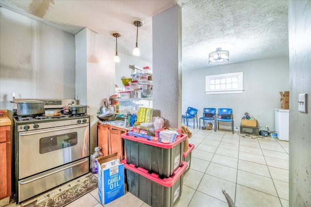 kitchen featuring light tile patterned floors, stainless steel gas stove, decorative light fixtures, and a textured ceiling