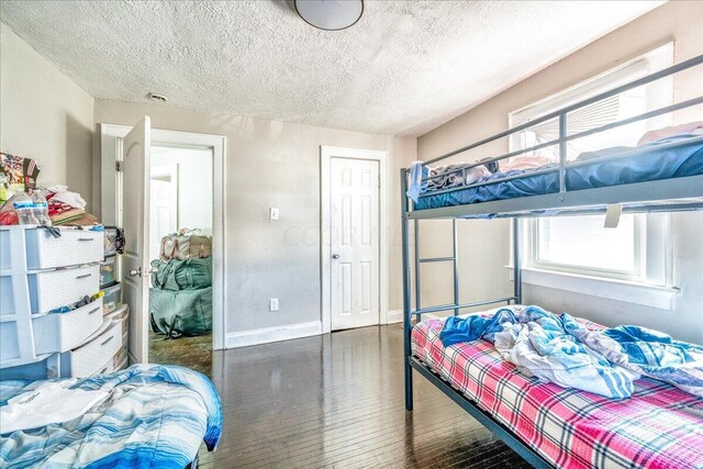 bedroom with a textured ceiling, multiple windows, and dark hardwood / wood-style floors