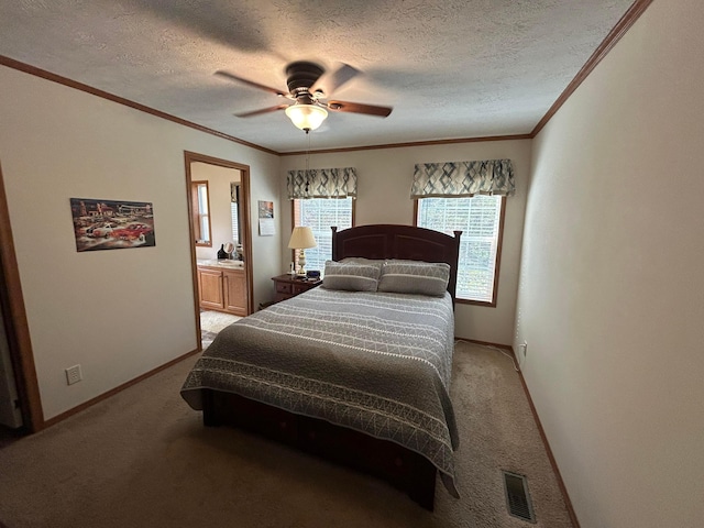 carpeted bedroom with a textured ceiling, ensuite bath, ceiling fan, and crown molding