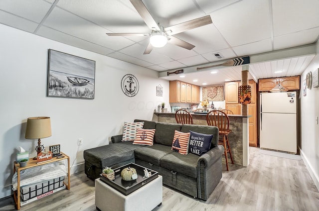 living room with light hardwood / wood-style floors, a drop ceiling, and ceiling fan