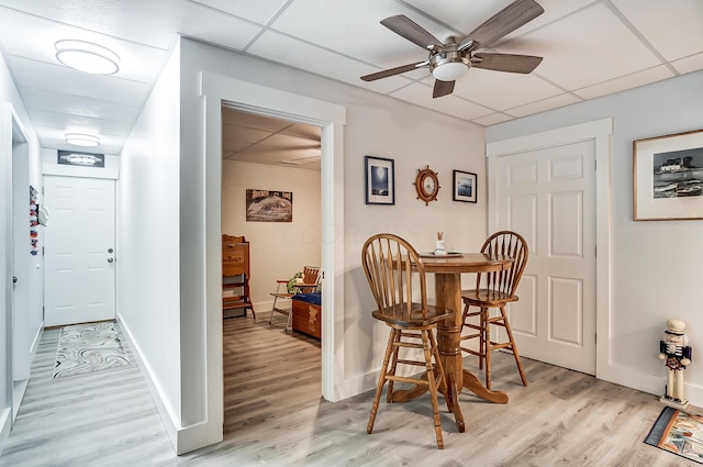 dining space featuring a paneled ceiling, ceiling fan, and light wood-type flooring