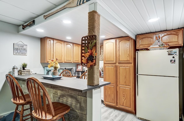 kitchen with a kitchen breakfast bar, kitchen peninsula, light hardwood / wood-style flooring, and white fridge