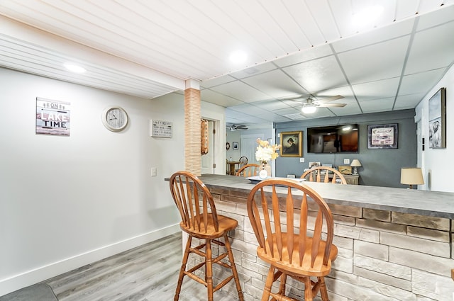 bar with a paneled ceiling, ceiling fan, and hardwood / wood-style floors