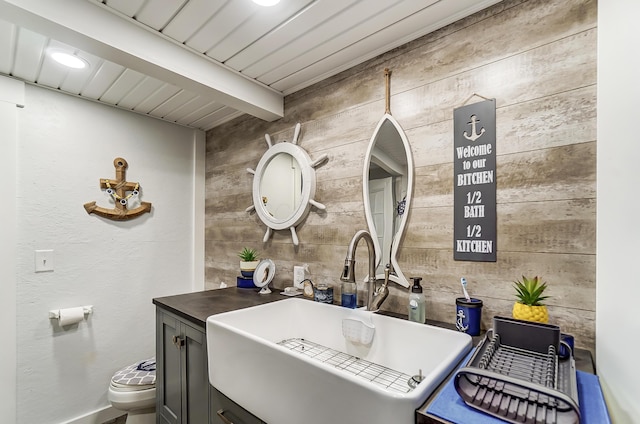 bathroom with beam ceiling, sink, and toilet