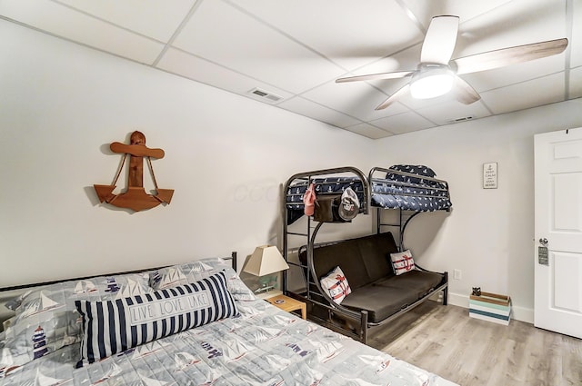 bedroom with ceiling fan, a drop ceiling, and hardwood / wood-style flooring