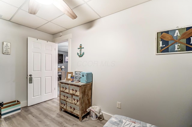 bedroom with light wood-type flooring, a drop ceiling, and ceiling fan