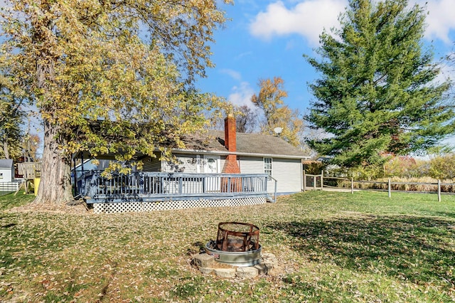 back of house featuring a yard, a deck, and an outdoor fire pit