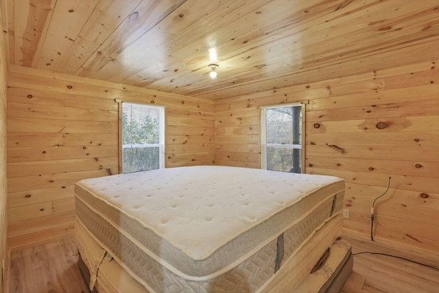 bedroom with wood walls, light hardwood / wood-style floors, and wooden ceiling