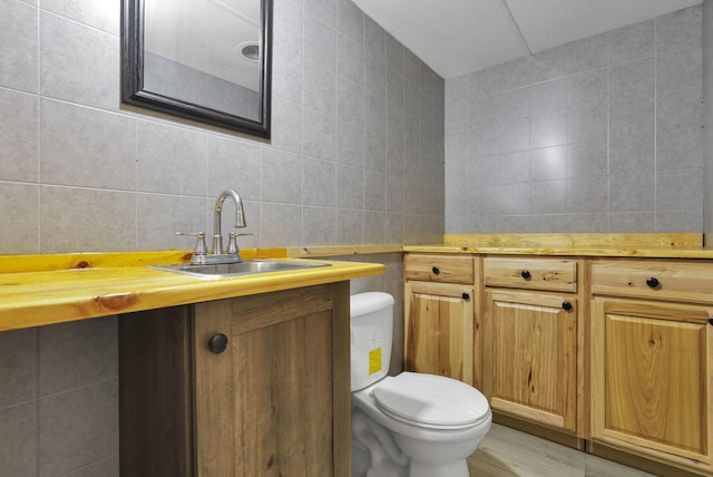 bathroom with hardwood / wood-style floors, vanity, toilet, and tile walls