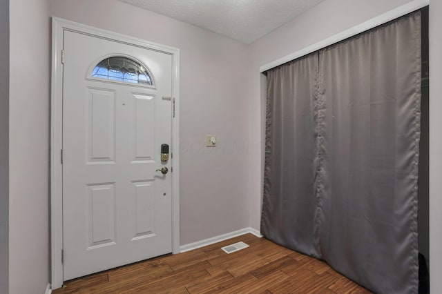 foyer entrance with dark wood-type flooring and a textured ceiling