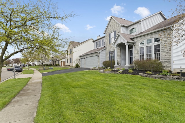 view of front facade with roof with shingles, a front yard, stone siding, driveway, and a residential view