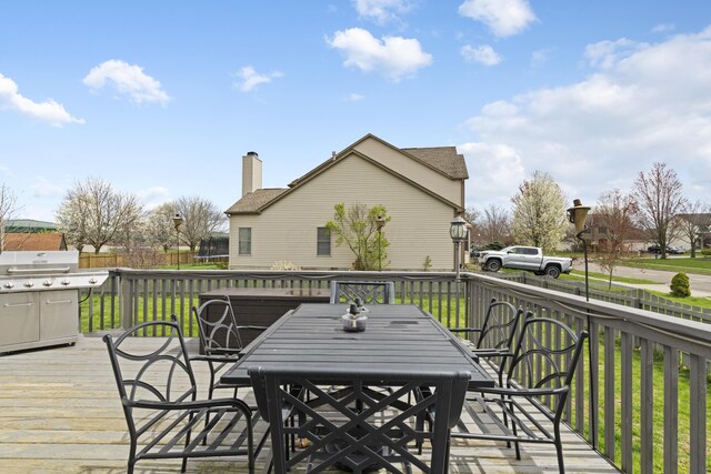 wooden deck featuring a trampoline, fence, a lawn, and outdoor dining space
