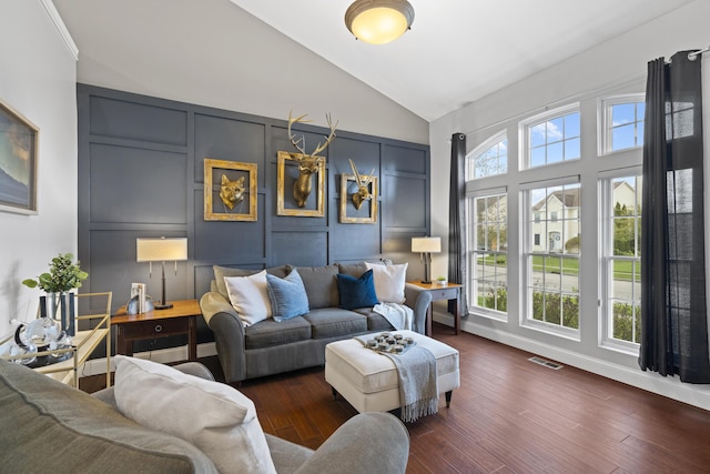 living area with a decorative wall, high vaulted ceiling, visible vents, and wood finished floors