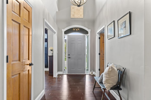entrance foyer with an inviting chandelier, baseboards, and dark wood-style floors