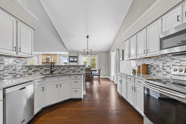 kitchen featuring vaulted ceiling, a peninsula, white cabinetry, stainless steel appliances, and a sink