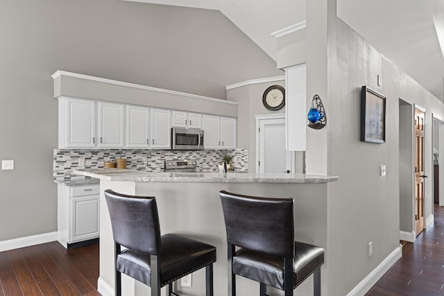 kitchen with tasteful backsplash, dark wood-style flooring, white cabinetry, and appliances with stainless steel finishes