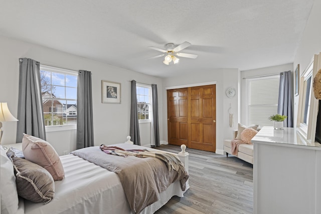 bedroom featuring light wood-type flooring, multiple windows, and ceiling fan