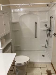 bathroom featuring tile patterned floors, a shower, vanity, and toilet