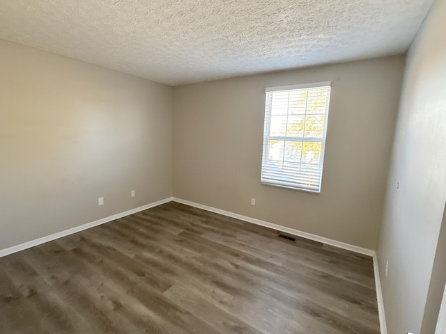 spare room with dark hardwood / wood-style flooring and a textured ceiling