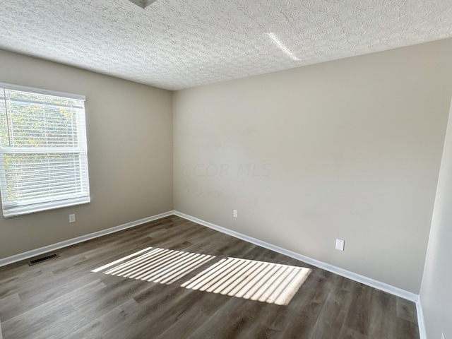 spare room with a textured ceiling and dark hardwood / wood-style flooring