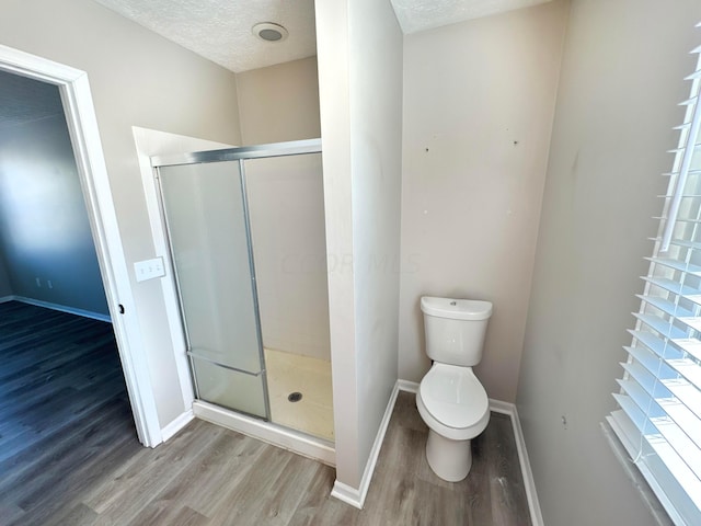 bathroom with hardwood / wood-style floors, a shower with door, and a textured ceiling