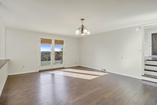 unfurnished room featuring dark wood-type flooring and an inviting chandelier