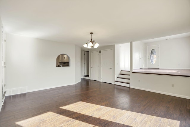 unfurnished living room featuring a chandelier and dark wood-type flooring