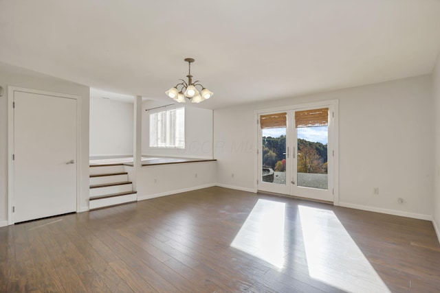 unfurnished room with dark wood-type flooring, a wealth of natural light, and an inviting chandelier